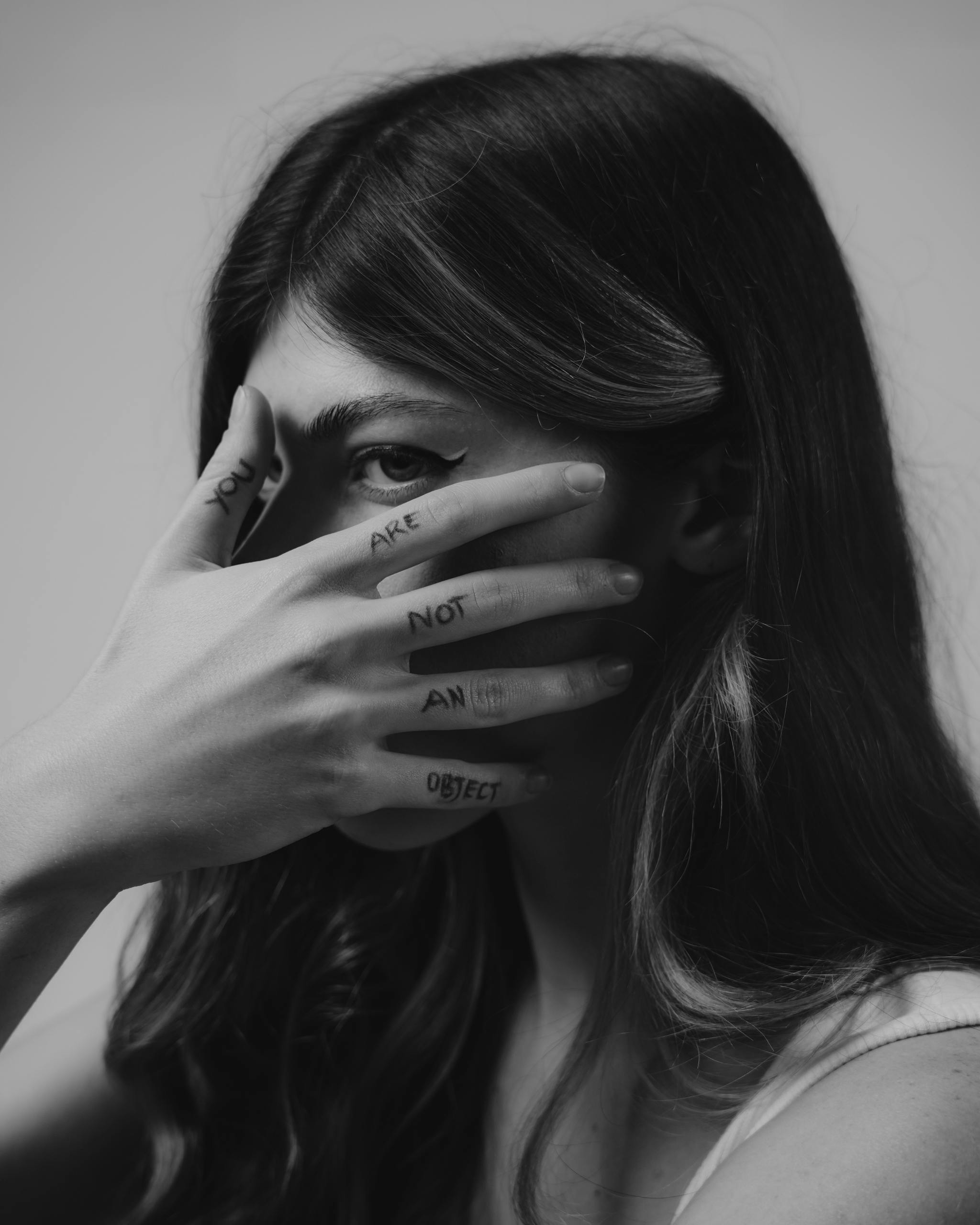 Close-up black and white portrait of a woman with empowering text on her fingers.