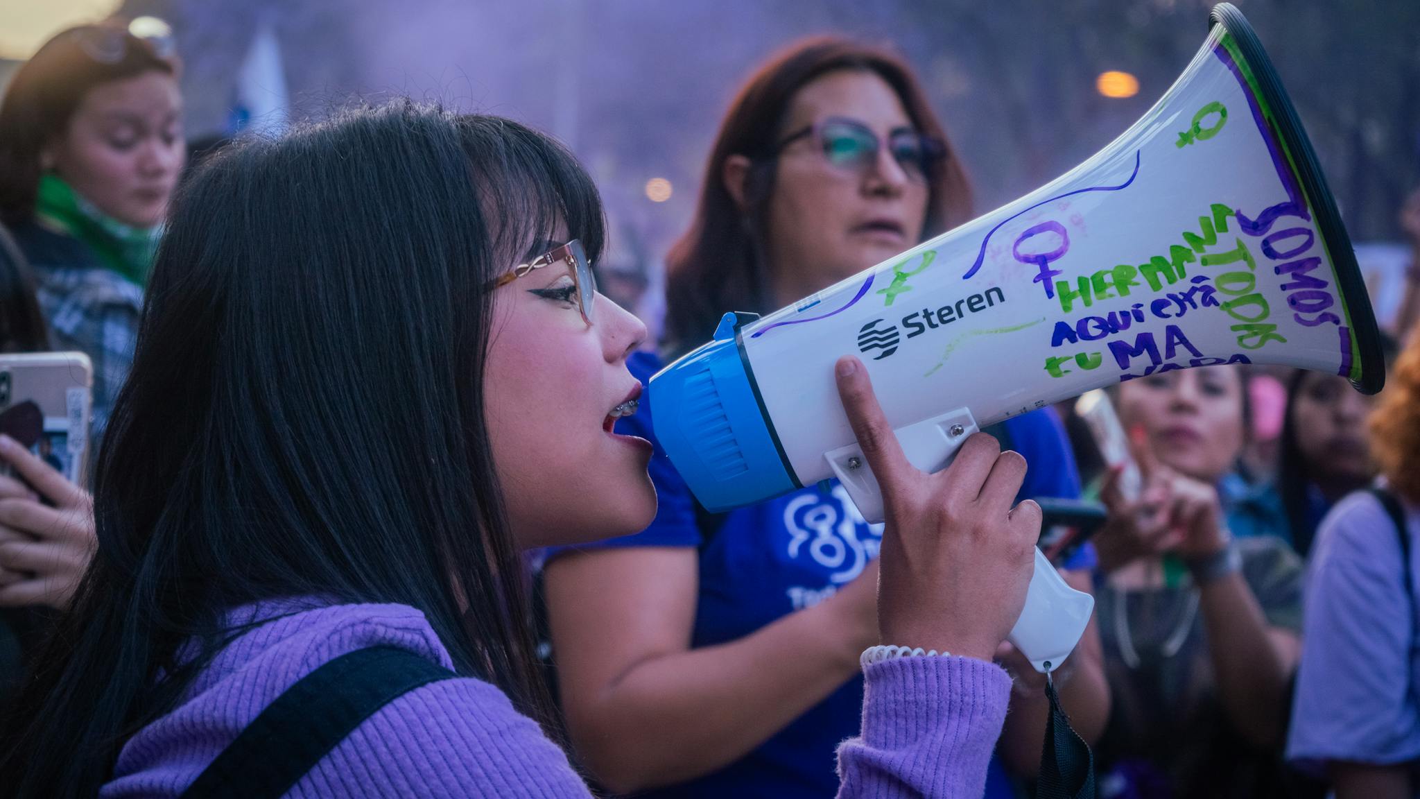 Young woman using megaphone during outdoor protest event, advocating empowerment.